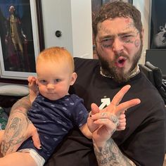 a man holding a baby in his arms and making the peace sign with both hands