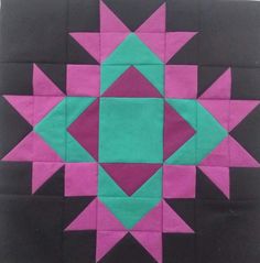 a black and pink quilt with green and purple designs on it's center piece