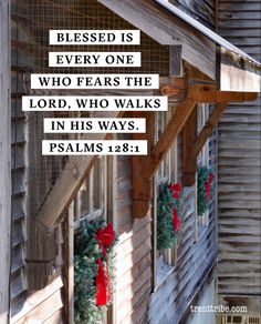 a wooden building with christmas wreaths on it and a bible verse written in white