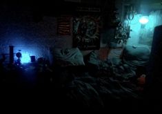 a dark room with a bed and some lights on the wall in front of it