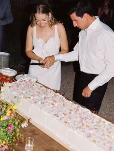 a man and woman cutting into a cake