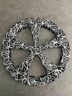 a metal peace sign sitting on top of a cement floor covered in filigrees