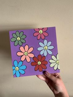 a hand holding up a piece of paper with flowers painted on it