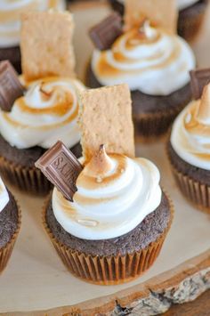 chocolate cupcakes with white frosting and caramel toppings on a wooden platter