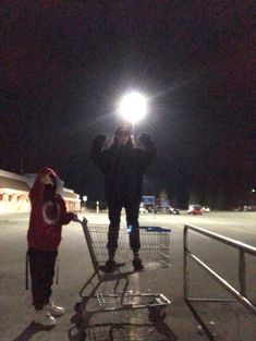 two people standing in front of a shopping cart at night