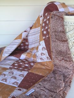 a close up of a quilt on a bed with white walls in the back ground