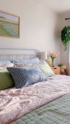 a bed sitting in a bedroom next to a window filled with flowers and blankets on top of it