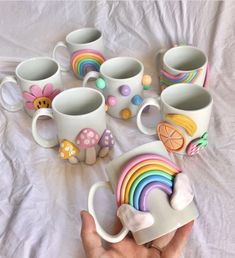 a hand holding a coffee cup with many different designs on the cups and saucers