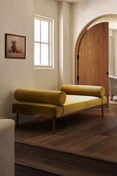 a yellow couch sitting on top of a hard wood floor next to a wooden door