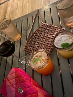 various drinks are sitting on a table next to glasses and a handbag with a green leaf