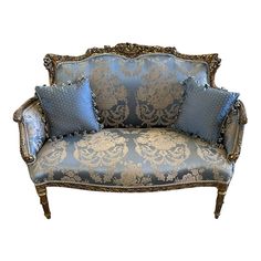 an ornate couch with blue and gold pillows on it's back, against a white background