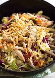 a salad with chicken, carrots and coleslaw in a black bowl