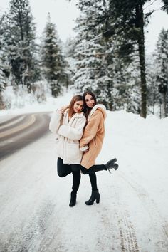 two women standing in the middle of a snowy road