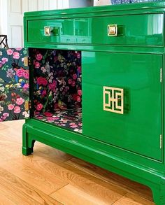 a green cabinet with flowers painted on the front and side panels is sitting on a hard wood floor