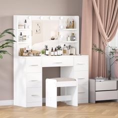 a white vanity with lights on it and a mirror in the corner next to a potted plant