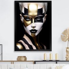 a woman's face is painted in gold and black on a white wall above a couch