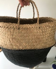 a hand holding a woven basket on top of a table