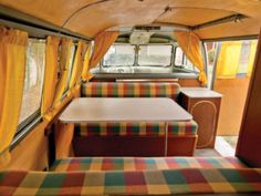 the interior of an rv with colorful curtains and plaid couches, including a dining table