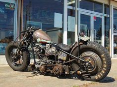 an old motorcycle is parked in front of a building with large windows and glass doors