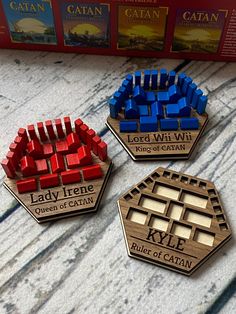 three wooden magnets with the words lady trene and king of catan on them