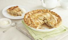 a pie sitting on top of a white plate next to a cup and saucer