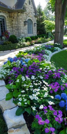 a flower bed with purple and white flowers in front of a house