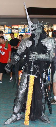 a man dressed up as a knight in an airport lobby with other people around him