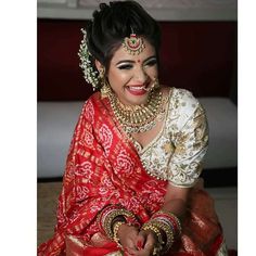 a woman in a red and white sari sitting on the floor with her hands clasped together