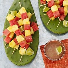 fruit skewers are arranged on top of green plates