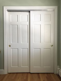 an empty room with two white doors and hard wood flooring on either side of the door