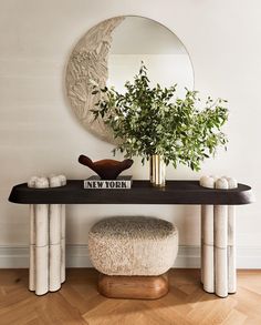 a table with a mirror and vase on top of it next to a plant in a vase