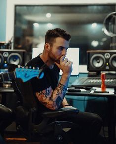 a man with tattoos sitting in front of a computer