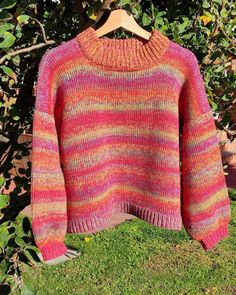 a pink and orange sweater hanging from a tree