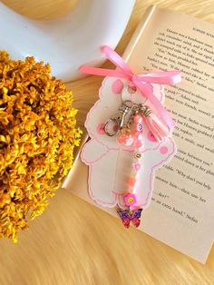 a bookmark and keychain on top of an open book next to flowers