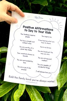 someone holding up a poster with the words positive affirmations to say to their kids