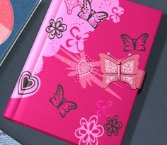 a pink notebook with butterflies and hearts on it