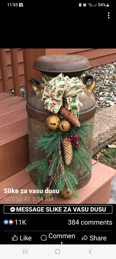 an old tin can decorated with pine cones and evergreens is on the porch for christmas