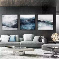 a living room filled with gray couches and paintings on the wall above them,