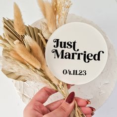 a button with the words just married on it and dried grass in front of it