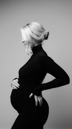 a pregnant woman poses for a black and white photo with her hands on her hips