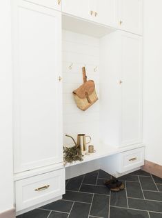 a kitchen with white cabinets and gray tile flooring on the walls, along with a wooden cutting board mounted to the wall