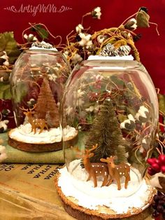 two snow globes with christmas trees and deer in them on top of a table