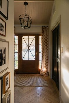 an entry way with pictures on the wall and a chandelier hanging from the ceiling