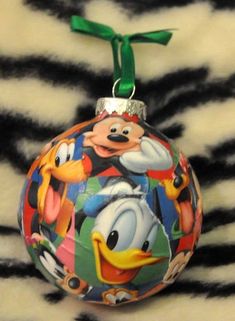 a mickey mouse ornament is hanging on a zebra print fabric with a green ribbon