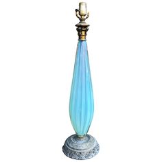 a blue glass lamp with a gold top on a white base and a golden candle holder in the middle