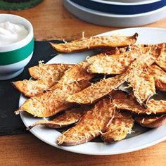 a white plate topped with cheesy fries next to a bowl of sour cream