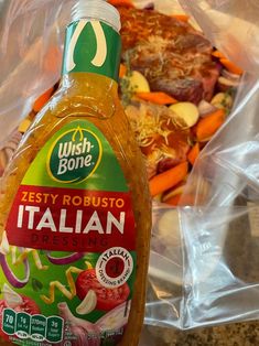 a bottle of salad dressing sitting on top of a counter next to a bowl of vegetables