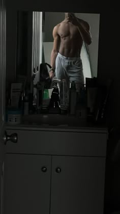 a shirtless man standing in front of a mirror