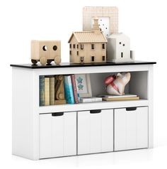 a book shelf with some books on top of it and two toy houses in the background