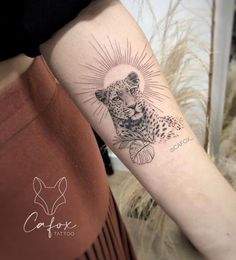 a woman's arm with a tattoo on it that has a cheetah in the center